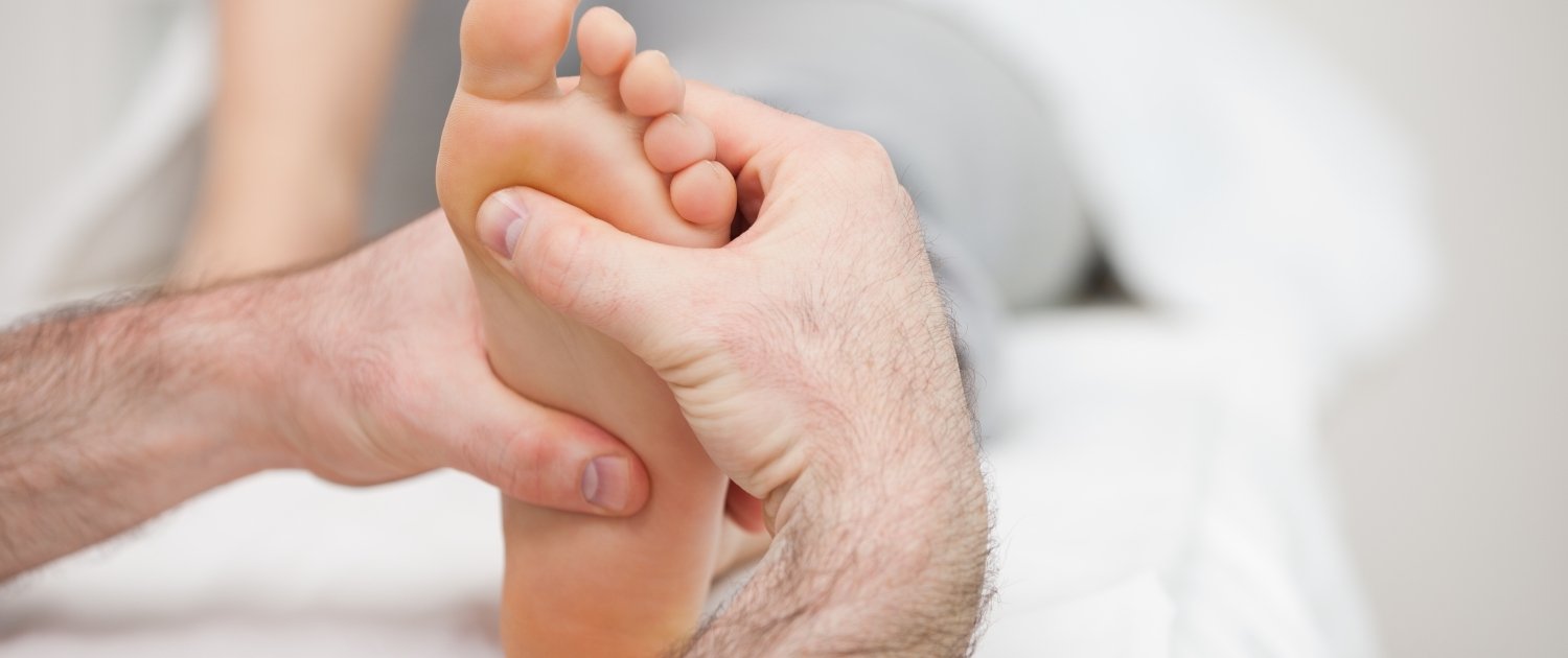 Man using his two hands to massage a foot in a room